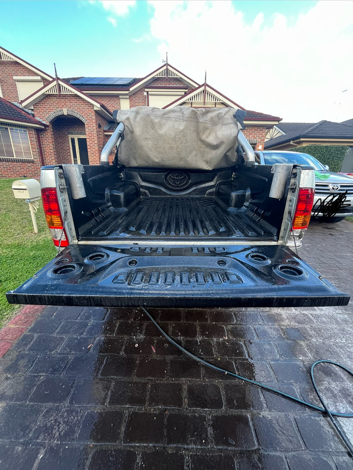 Freshly washed ute with a clean tray and tailgate on a wet driveway